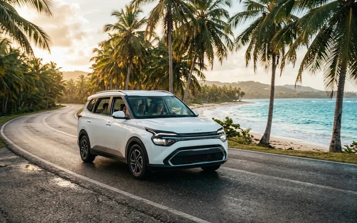 White Kia Carens 2026 SUV driving along a palm-lined coastal road in Punta Cana